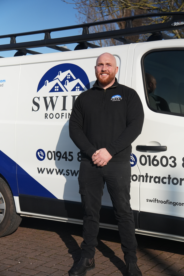 Luke Crosby, owner of Swift Roofing Contractors, standing in front of the company van